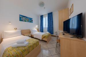 マルゲーラにあるHotel Nuova Auroraのベッド2台、薄型テレビが備わるホテルルームです。