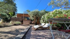 un patio con un banco y una silla y una casa en Lodge Les Oliviers en Garéoult