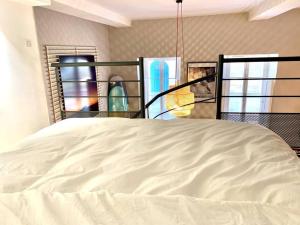 a large white bed in a room with windows at Charming apartment in the Chartrons district in Bordeaux