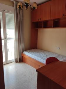 um pequeno quarto com uma cama e uma janela em Piso Loli em Málaga