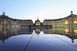 a large building with its reflection in the water at Charming apartment in the Chartrons district in Bordeaux