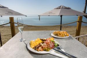 a table with two plates of food and a glass of wine at Olive Villas Beach Hotel in Sozopol