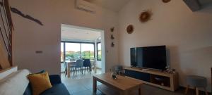 - un salon avec une télévision, un canapé et une table dans l'établissement location maison de vacances jusqu'à 6 personnes près du port et de la plage, au Barcarès
