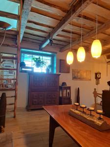 a dining room with a wooden table and lights at Macskajaj vendégház in Mecseknádasd