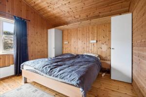 een slaapkamer met een bed in een houten muur bij Romslig hytte med natur og gode fiskemuligheter! in Lødingen