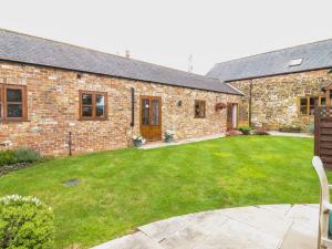 a brick house with a lawn in front of it at Mistal Cottage in Husthwaite