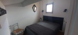 um pequeno quarto com uma cama e uma janela em location maison de vacances jusqu'à 6 personnes près du port et de la plage em Le Barcarès