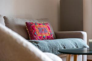 a brown couch with a colorful pillow on it at SUNSHINE - Appartement 2pers - terrasse vue mer - Dinard in Dinard