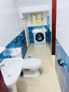 a bathroom with a toilet and a washing machine at Spacieuse maison à Calavi - Comme chez vous in Abomey-Calavi