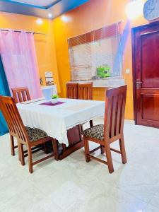 cocina con mesa blanca, sillas y reloj en Spacieuse maison à Calavi - Comme chez vous en Abomey-Calavi