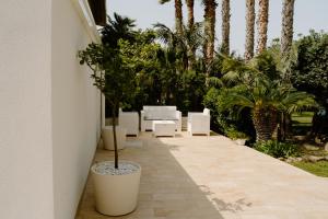 a patio with white chairs and palm trees at Villa Angelica - Casa Vacanze in Reggio di Calabria