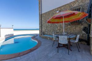 einen Tisch mit einem Sonnenschirm neben einem Pool in der Unterkunft casa vacanza barbera - In Riva al Mare in Trappeto
