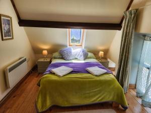 Schlafzimmer mit einem Bett mit lila Bettwäsche und Kissen in der Unterkunft The Old School Caeathro, Snowdon, Eryri and Yr Wydffa Cottages in Caernarfon