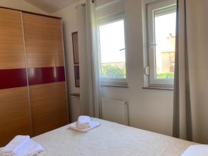 a bedroom with a bed and a dresser and two windows at Apartment Anabella in Fažana