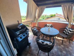 a balcony with a grill and a table and chairs at Apartment Anabella in Fažana