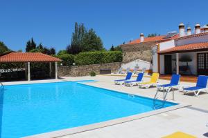 a swimming pool with chairs and a house at Casa de Campo Sao Rafael - Turismo Rural in Óbidos