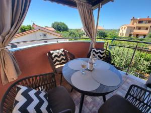 a patio with two tables and chairs on a balcony at Apartment Anabella in Fažana
