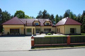 a house with a fence in front of it at Rezydencja Nad Wigrami Standard & Comfort Rooms in Gawrych Ruda