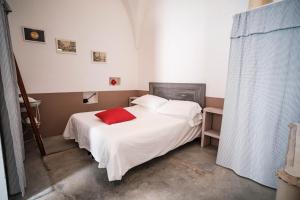 een slaapkamer met een wit bed en een rood kussen bij Casa Le Mura in Ostuni