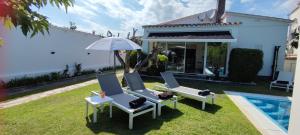 a yard with two chairs and an umbrella and a pool at Bahía 66 in Empuriabrava