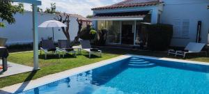 a pool with chairs and an umbrella next to a house at Bahía 66 in Empuriabrava