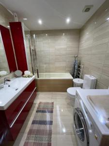 a bathroom with a tub and a washing machine in it at Cozy Apartment, Jaukus Butas Centre, internet in Klaipėda +10 photos