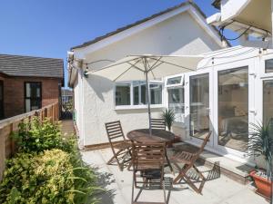 a patio with a table and chairs and an umbrella at Seagull Cottage in Holyhead