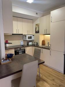 a kitchen with white cabinets and a table and chairs at Cozy Apartment, Jaukus Butas Centre, internet in Klaipėda