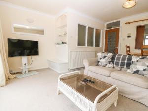 a living room with a couch and a tv at 11 Min Y Mor in Pwllheli