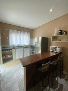 a kitchen with a counter with two chairs and a refrigerator at Mares de Camburizinho in Camburi