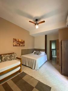 a bedroom with a bed and a ceiling fan at Mares de Camburizinho in Camburi