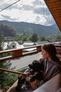 Eine Frau, die mit einem Hund auf einer Veranda sitzt. in der Unterkunft Готель Довбуш in Jaremtsche