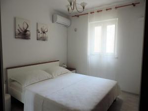 a bedroom with a white bed and a window at Rooms & studio OLD TOWN PAG in Pag