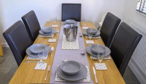 a long wooden table with chairs and plates and glasses at APPLEDOWN - Secluded Rural Retreat in Kingsdown, 10 mins to BEACH in Kent