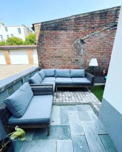 a patio with blue couches on a brick wall at Sfeervolle vakantiewoning aan zee in Ostend