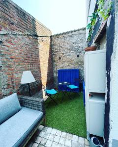 a patio with a couch and a table and a refrigerator at Sfeervolle vakantiewoning aan zee in Ostend