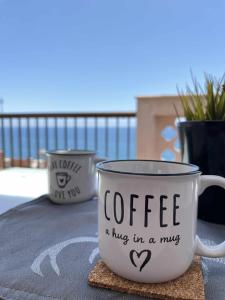 een koffiemok die zegt koffie een knuffel in een mok bij Ático con terraza frente al mar Playa Zapillo in Almería
