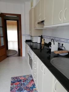 uma cozinha com electrodomésticos brancos e uma bancada preta em Ático Río Pego em Ángeles