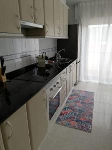 uma cozinha com armários brancos e um balcão preto em Ático Río Pego em Ángeles