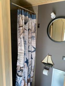 een badkamer met een douchegordijn en een spiegel bij Seaside holiday home Vecvalki in Saunags