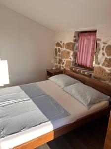 Bett in einem Zimmer mit einer Steinmauer in der Unterkunft konoba in Rab