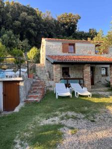 a stone house with two chairs and a table at konoba in Rab