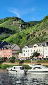 two boats are docked in the water near a village at Ferienwohnung Roter Riesling in Zell an der Mosel