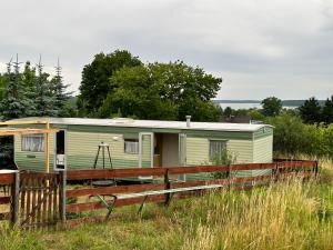 una caravana verde en un campo con una valla en Domek za świerkami en Charzykowy