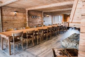 a long table and chairs in a room with wooden walls at Alpage la Grand Montagne 1858 in Le Grand-Bornand