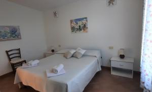 a white bedroom with two beds and a chair at MaLù House in Villasimius