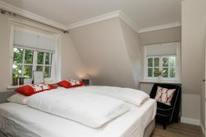 ein Schlafzimmer mit einem großen weißen Bett mit roten Kissen in der Unterkunft Südwind´s Friesenlodge in Tinnum