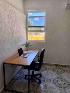 a desk with a laptop computer on it with a window at Apartment located two blocks from the sea in Cozumel