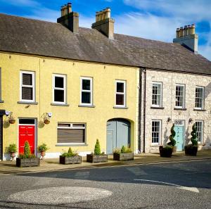 una casa gialla con una porta rossa su una strada di Rose House a Glenarm