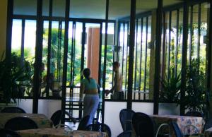 a woman standing on a balcony looking into a room with windows at Residence Miralago Rooms & Apartments in Manerba del Garda